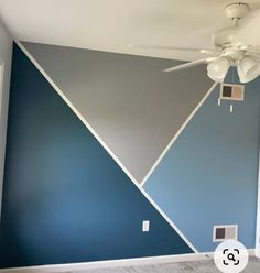 a ceiling fan in a room with blue and gray walls painted on the wall behind it