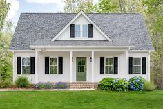 a white house with black shutters and green grass