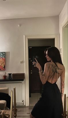 a woman standing in a living room with tattoos on her back