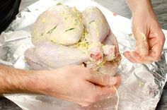 two hands are peeling chicken on tin foil