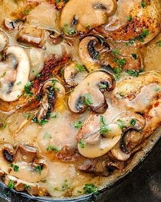 a skillet filled with chicken, mushrooms and parsley on top of a table