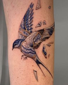 a blue bird flying through the air with an arrow in its beak tattoo design on leg