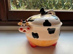 a ceramic pot with a cow head on it sitting in front of a window sill