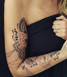 a woman's arm with tattoos on it and flowers in the middle of her arm