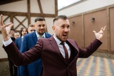 a man in a suit and tie is standing with his hands up while other men stand behind him