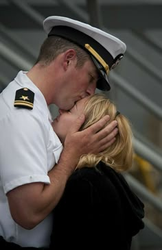 a man in uniform kissing a woman on the cheek