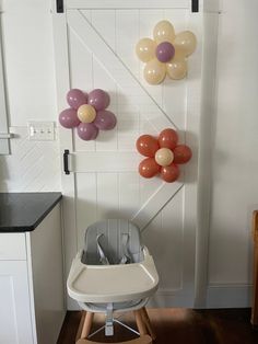 a baby's highchair with balloons attached to the wall and flowers on it