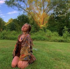 a woman sitting in the grass with her eyes closed