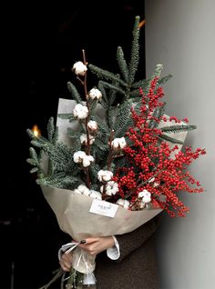 a person holding a bouquet of flowers and berries