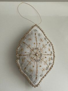 a white ornament hanging on a wall with beads and beaded trimmings