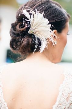 the back of a woman's head wearing a hair comb with feathers on it