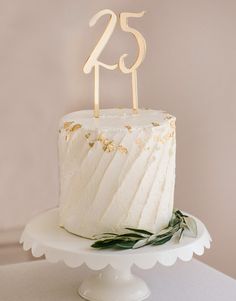 a white cake sitting on top of a table with the number twenty five on it