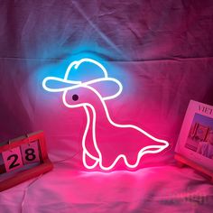 a neon sign with a woman's hat on it in front of a pink background