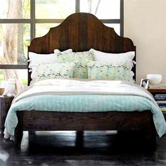 a bed sitting in front of a window next to a wooden headboard and foot board