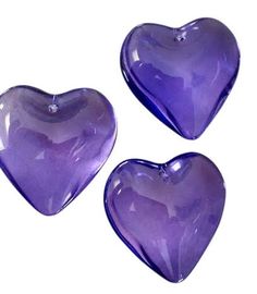 three purple heart shaped dishes sitting next to each other