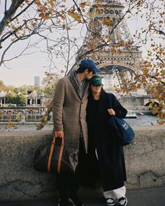 a man and woman standing next to each other near the eiffel tower in paris