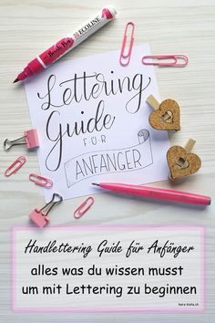 a pink pen and some paper clips on top of a white table with a sign that says, lettering guide for anhanger