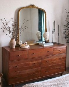 a dresser with a mirror and vases on it