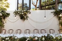 the table is set up with white flowers and greenery for an outdoor wedding reception