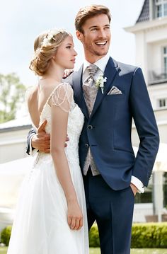 a bride and groom are posing for a wedding photo in front of a large building