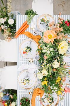 an overhead view of a table with plates, flowers and carrots on it in the center