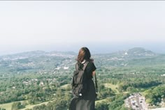 a woman standing on top of a mountain looking down