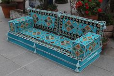 a blue couch sitting on top of a cement floor next to potted planters