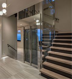 a staircase leading up to the top floor of a house with glass walls and metal handrails