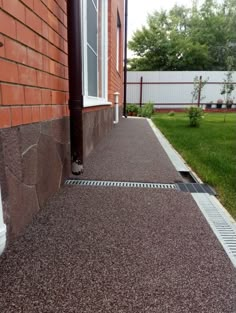 the side of a house with grass in front of it and a gutter hose attached to the ground