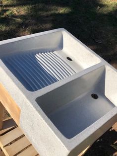 a white sink sitting on top of a wooden pallet next to a grass covered field