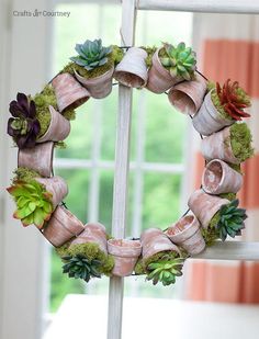 a wreath with succulents and other plants is hanging on a window sill