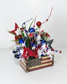 a patriotic arrangement in a wooden box with red, white and blue decorations on it