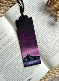 a bookmark with an image of mountains and stars on it, sitting on top of a book