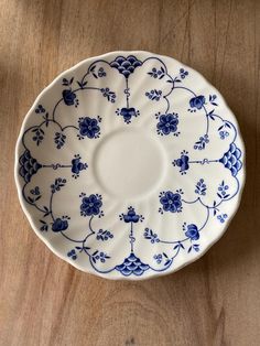 a blue and white plate sitting on top of a wooden table next to a wall