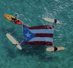 two people on surfboards holding an american flag in the water with other paddles