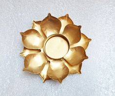 a gold flower shaped object on a white surface