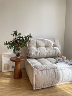 a white couch sitting on top of a wooden floor next to a vase with flowers