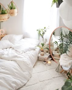 a bedroom with white bedding and lots of plants