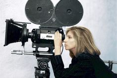 a woman is looking through the lens of an old movie camera on a tripod