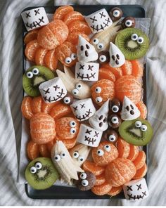 a tray filled with oranges and kiwi slices covered in fake eyes on top of each other