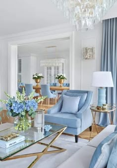 a living room filled with furniture and a chandelier above a glass coffee table