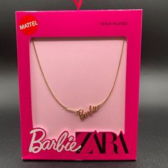 a gold necklace with the word barbie on it in front of a pink box that says barbie