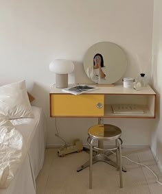 a bedroom with a bed, desk and mirror on the wall next to each other