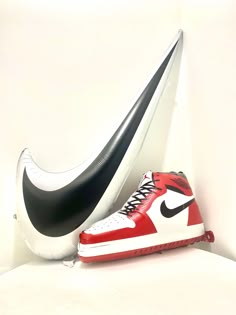 a pair of nike sneakers sitting on top of a white table next to a black and red shoe