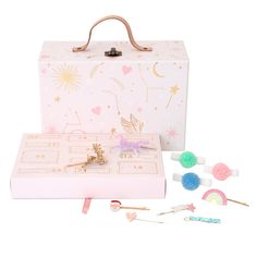 a pink suitcase with some pins and other items in front of it on a white background