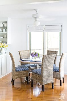 a dining room table with four chairs and a vase on top of it in front of a window