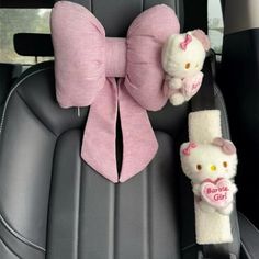 two hello kitty stuffed animals are in the back seat of a car with pink bows