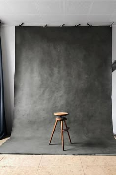 a chair sitting on top of a wooden stool in front of a gray backdrop