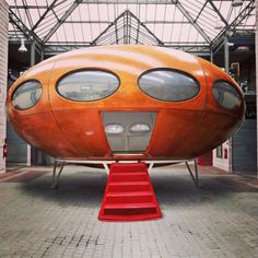 a large orange object sitting on top of a red step way next to a building