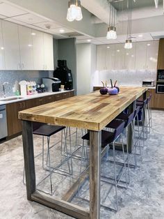 a kitchen with a wooden table surrounded by purple chairs and stools in front of the counter